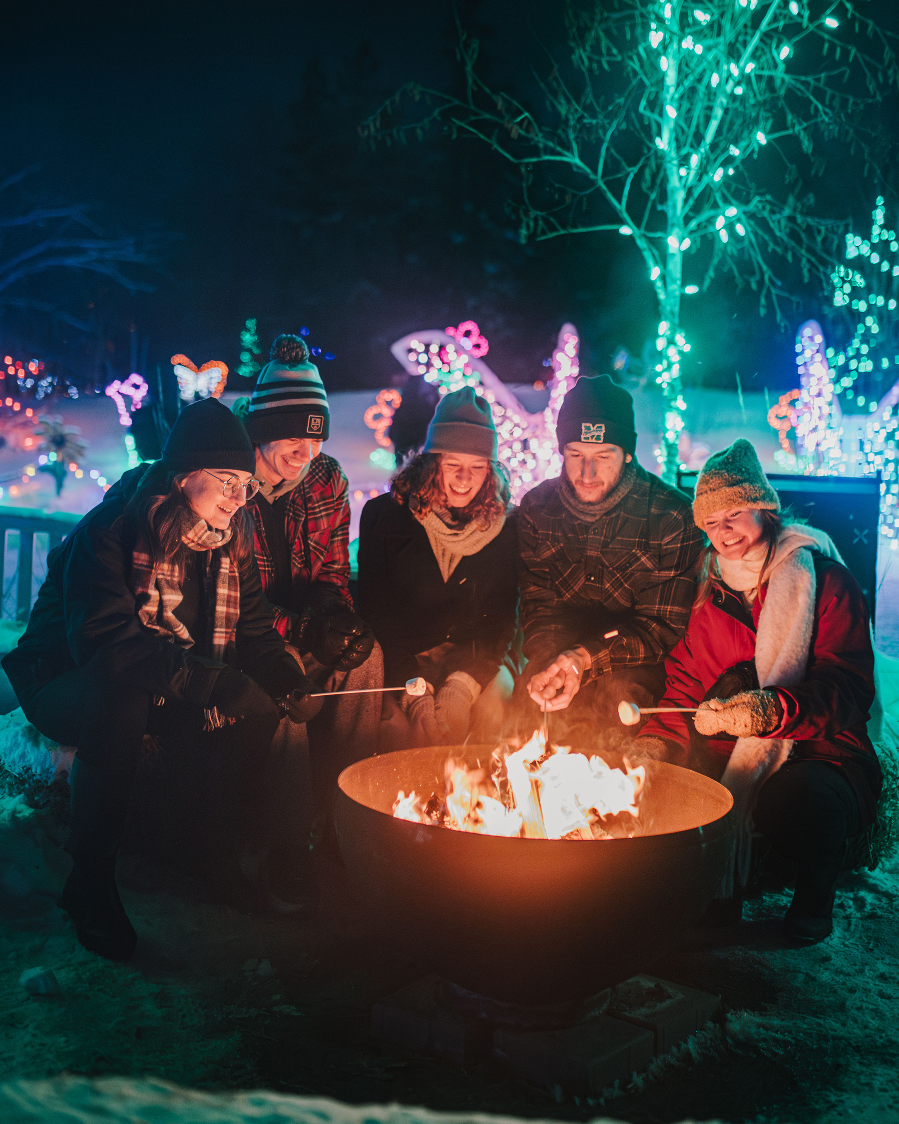 A group of friends gather around a firepit making s'mores